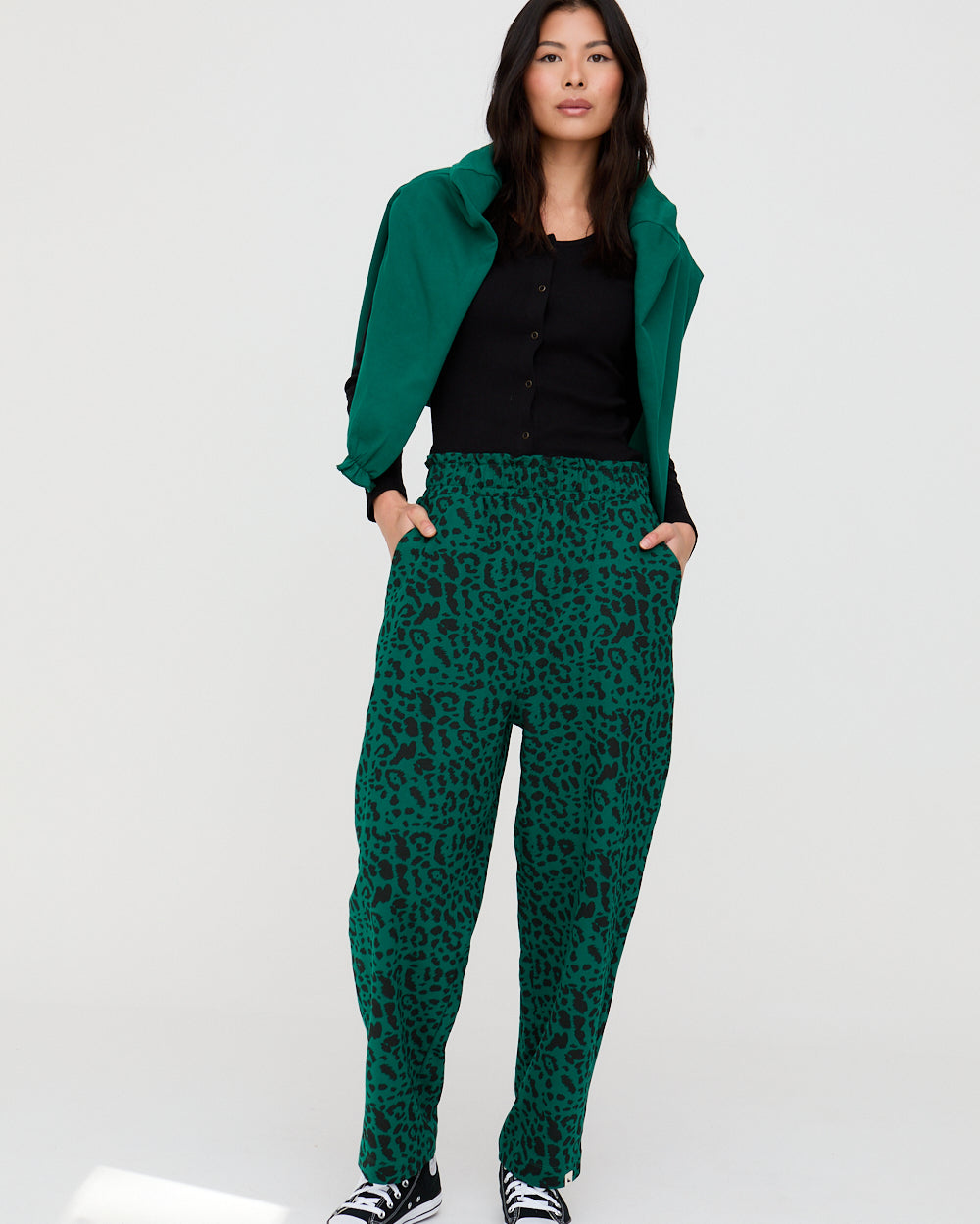 Person wearing a green jacket and green leopard print pants on a white background