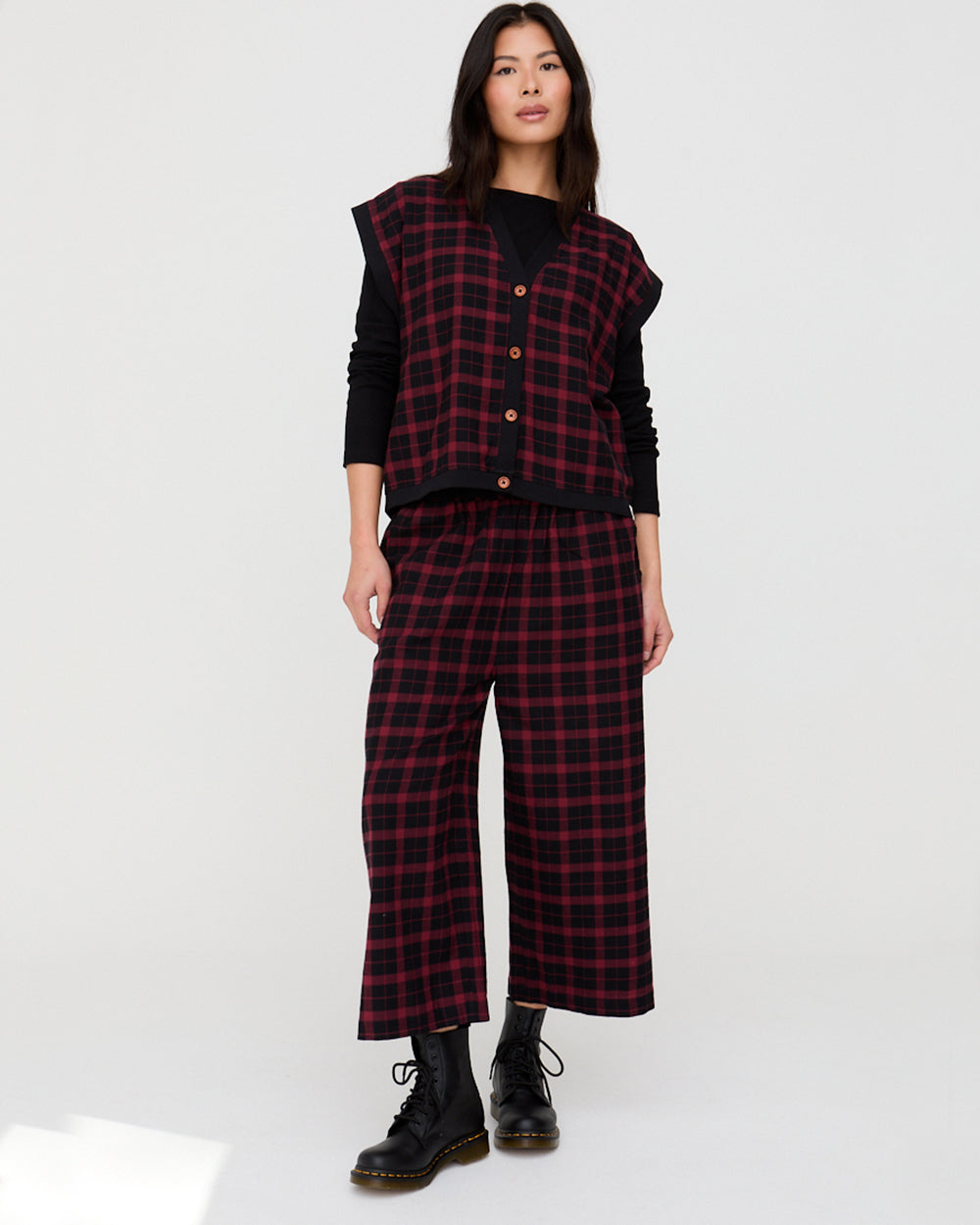Person wearing a red and black plaid outfit with a vest on a white background