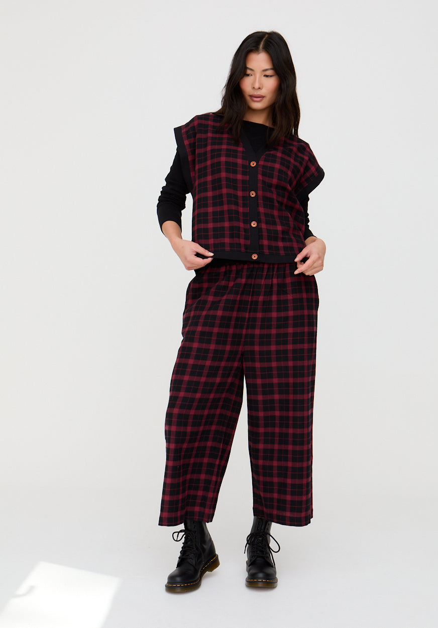Person wearing a red and black plaid outfit with a vest on a white background