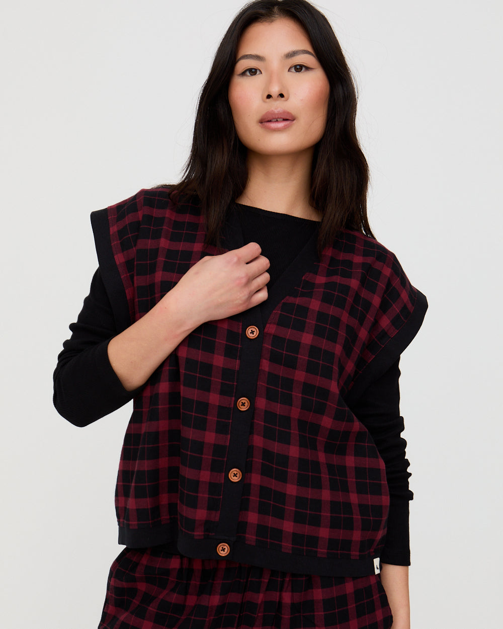 Woman wearing a black and red plaid cardigan on a white background