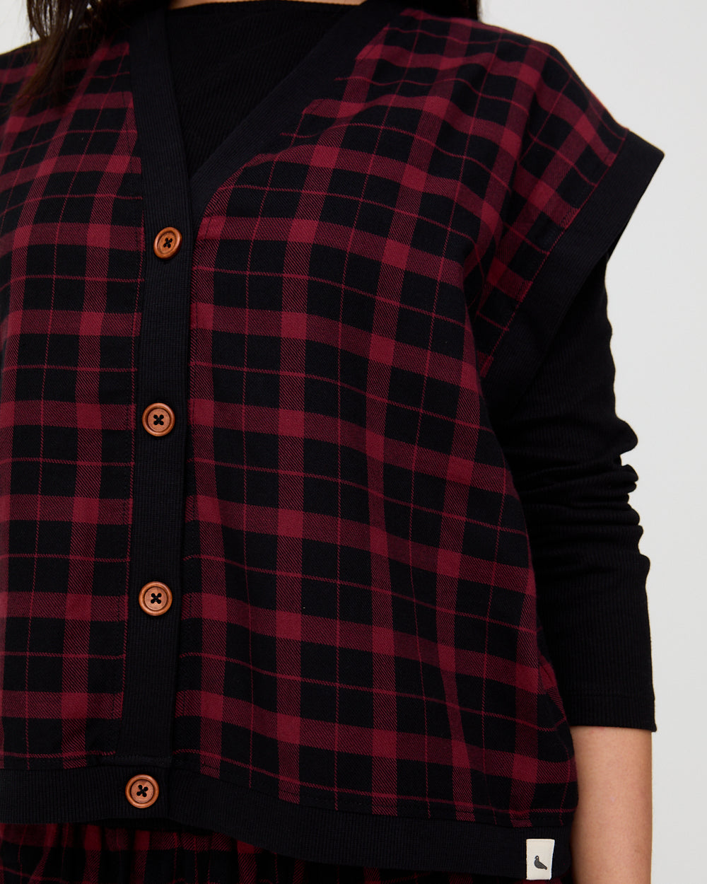 Red and black plaid vest over a black shirt on a white background