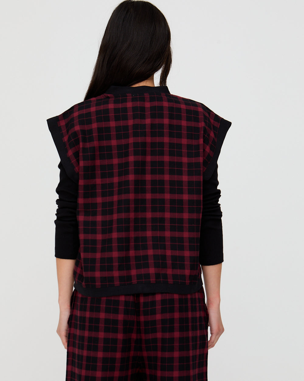 Person wearing a red and black plaid outfit with a plain background