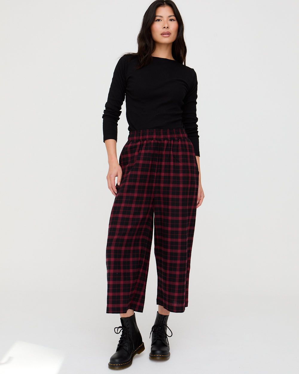 Woman wearing a black top and red plaid pants on a white background