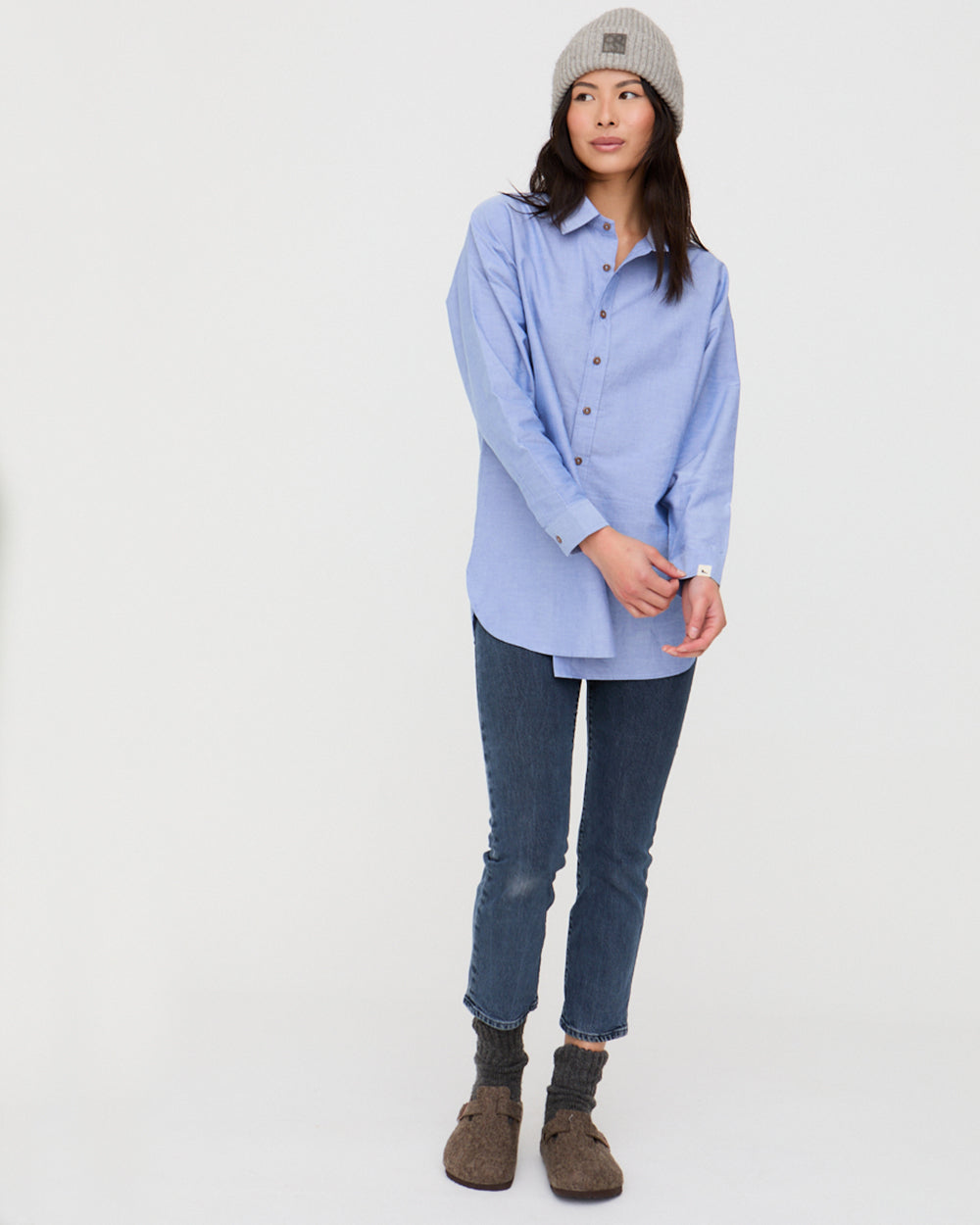 Person wearing a light blue shirt, dark jeans, and brown boots on a white background