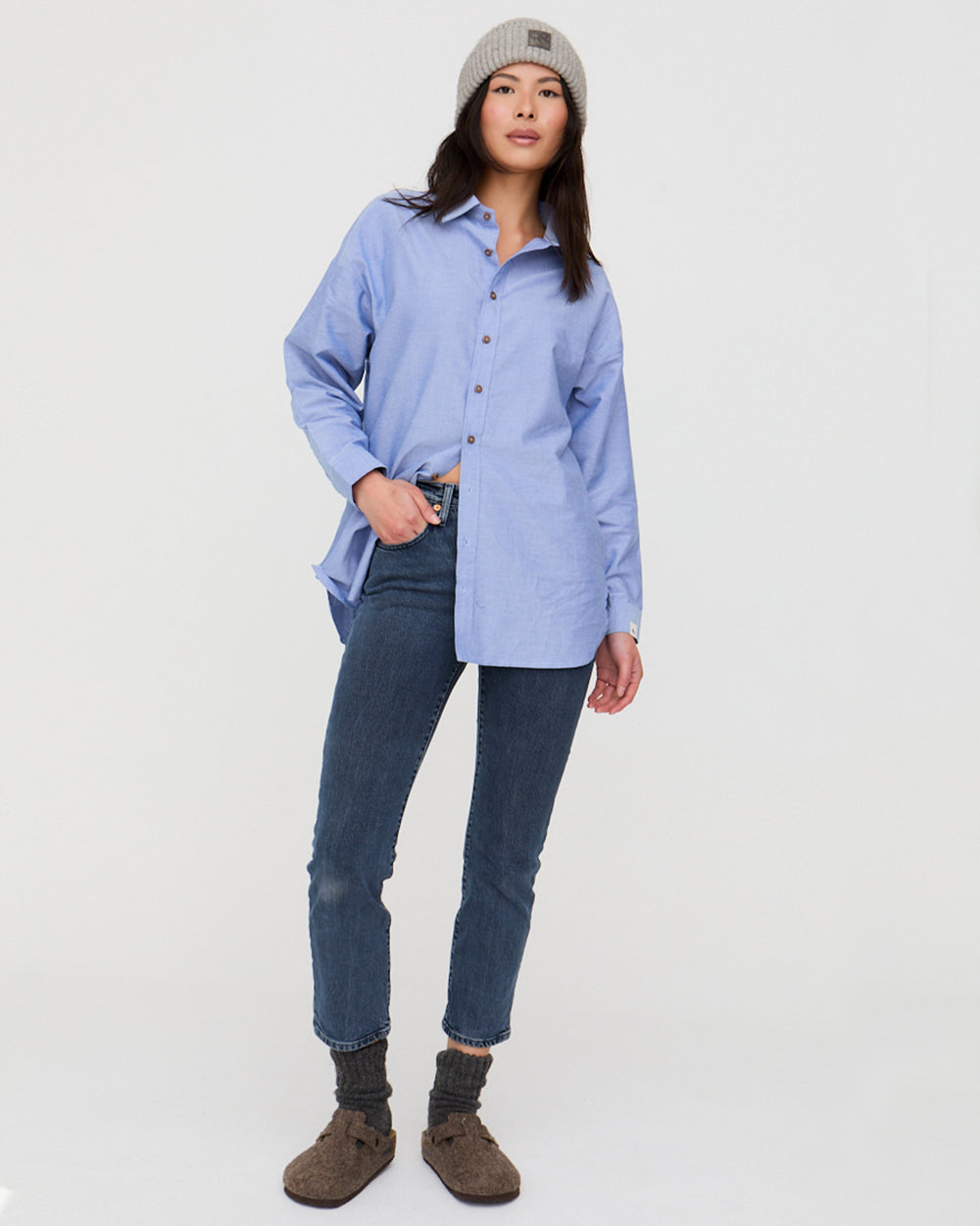 Person wearing a blue shirt, jeans, and brown boots on a white background