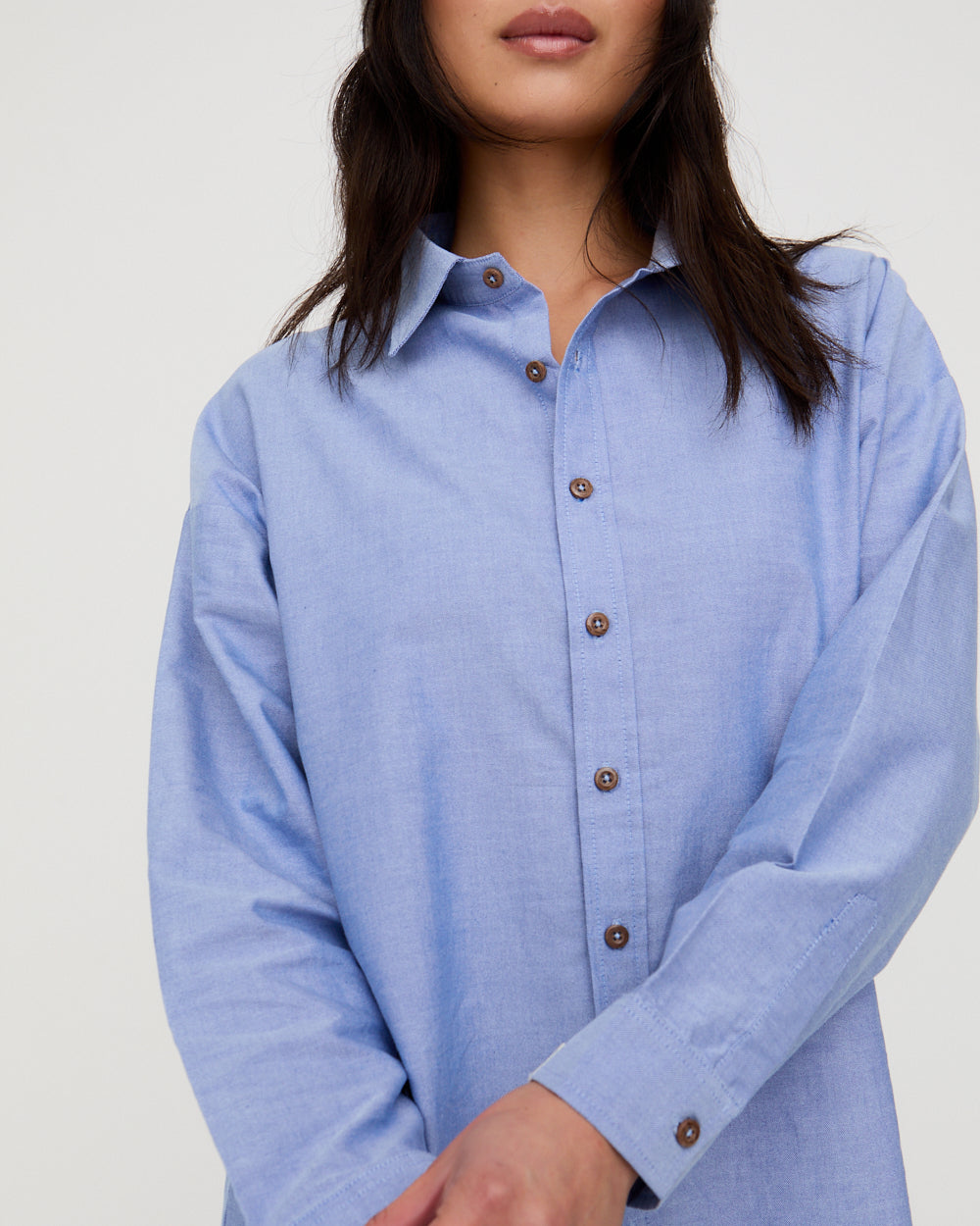 Woman wearing a light blue shirt with a plain background