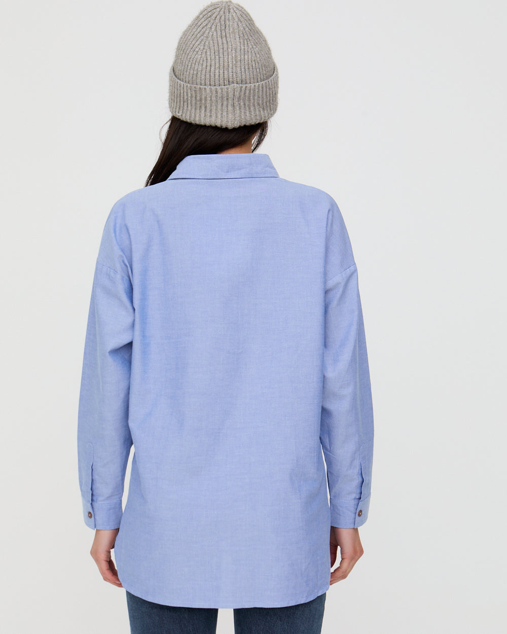Person wearing a light blue shirt and gray beanie on a plain background