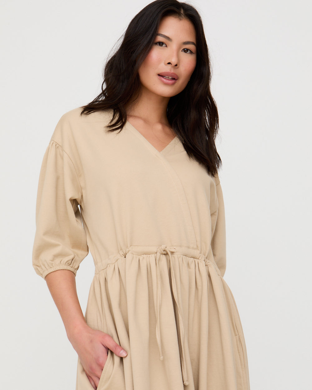 Woman wearing a beige dress against a white background