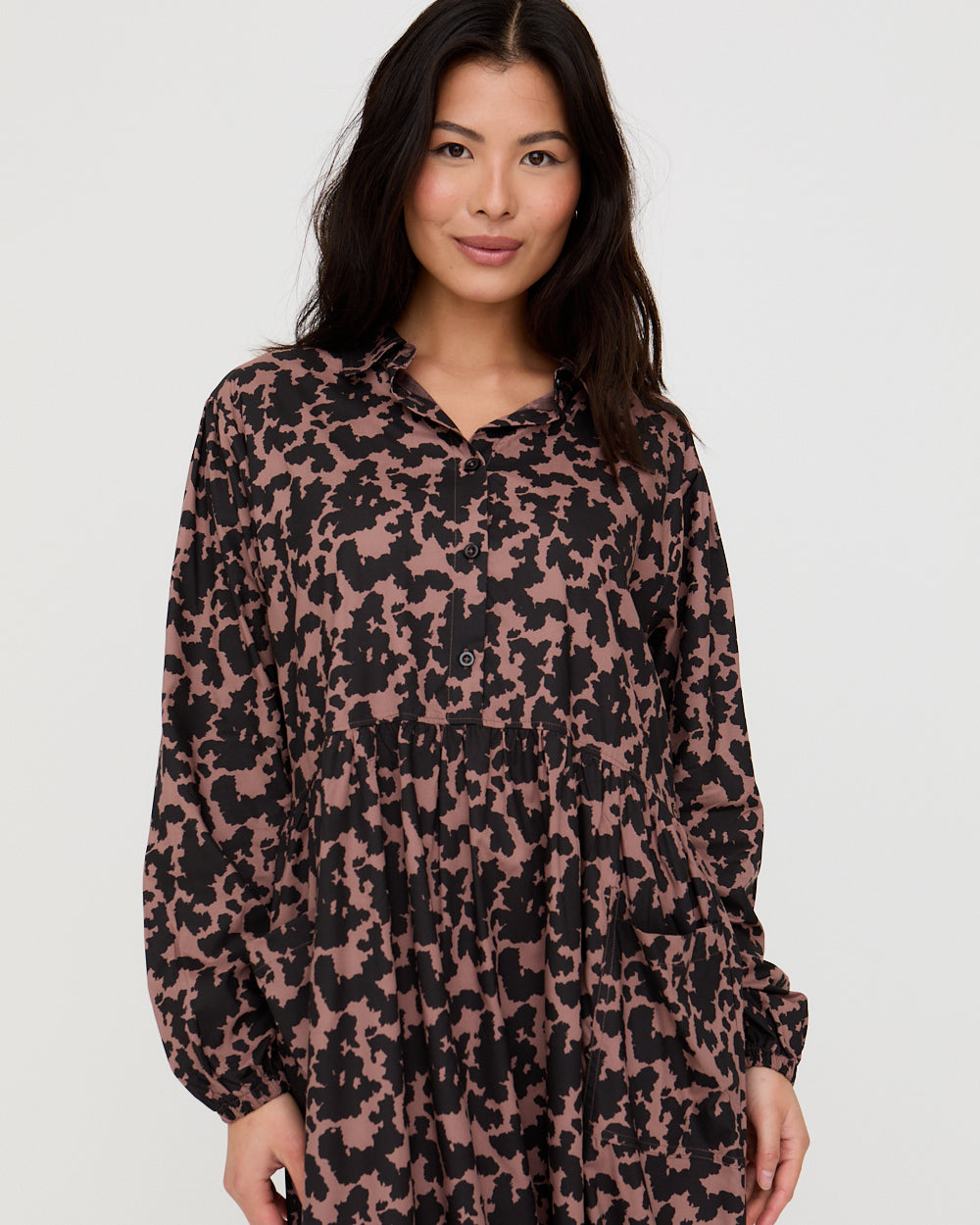 Woman wearing a long-sleeve shirt with a floral pattern on a plain background