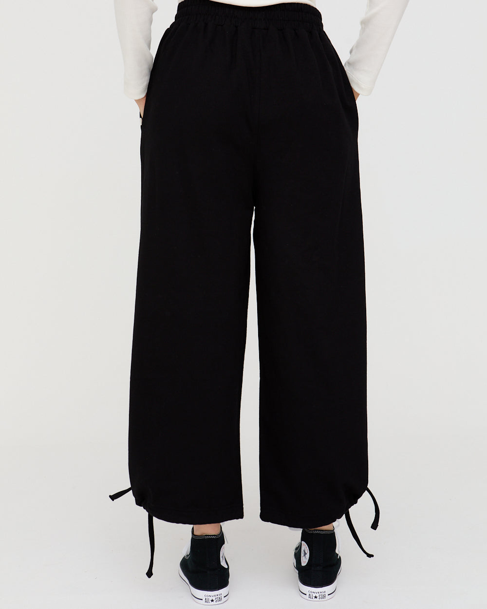 Black wide-leg pants worn by a person on a white background