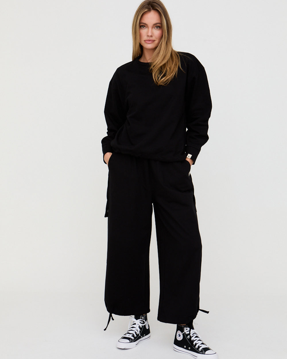 Person wearing a black outfit with wide-leg pants on a white background