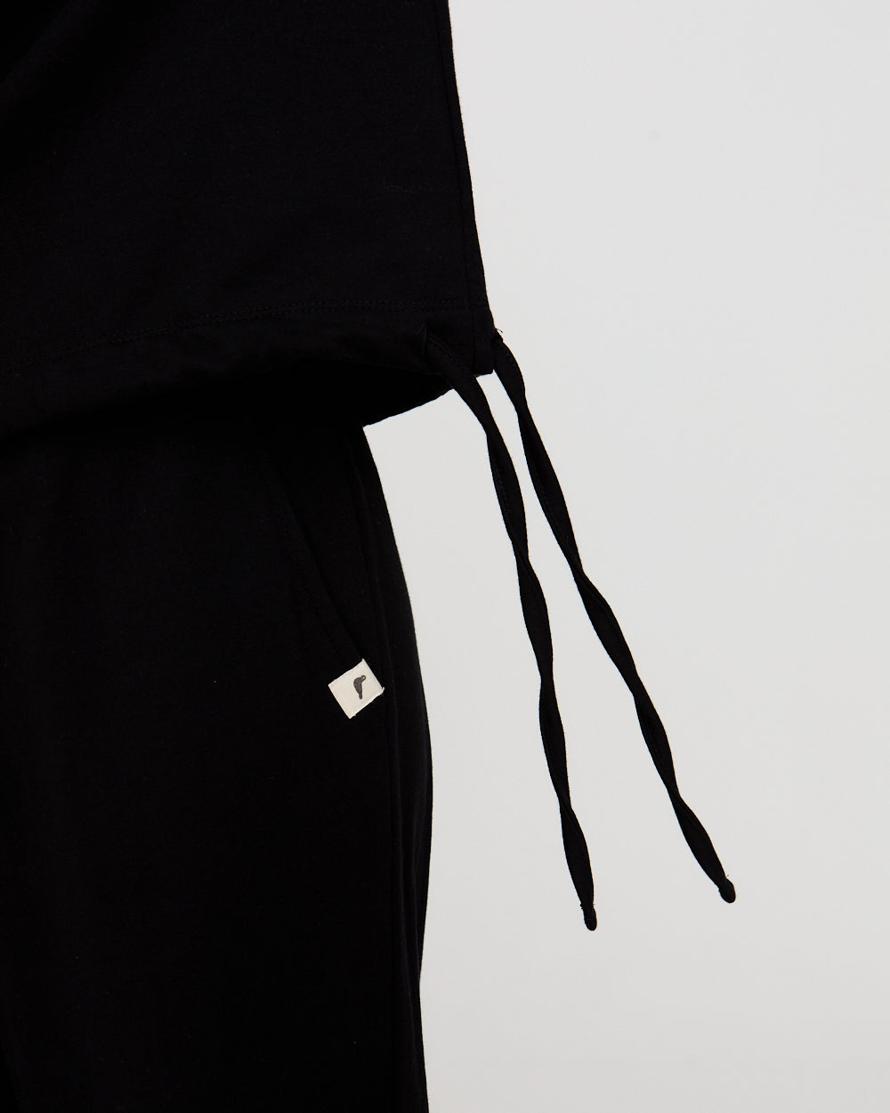 Black outfit with a small white logo on a light gray background