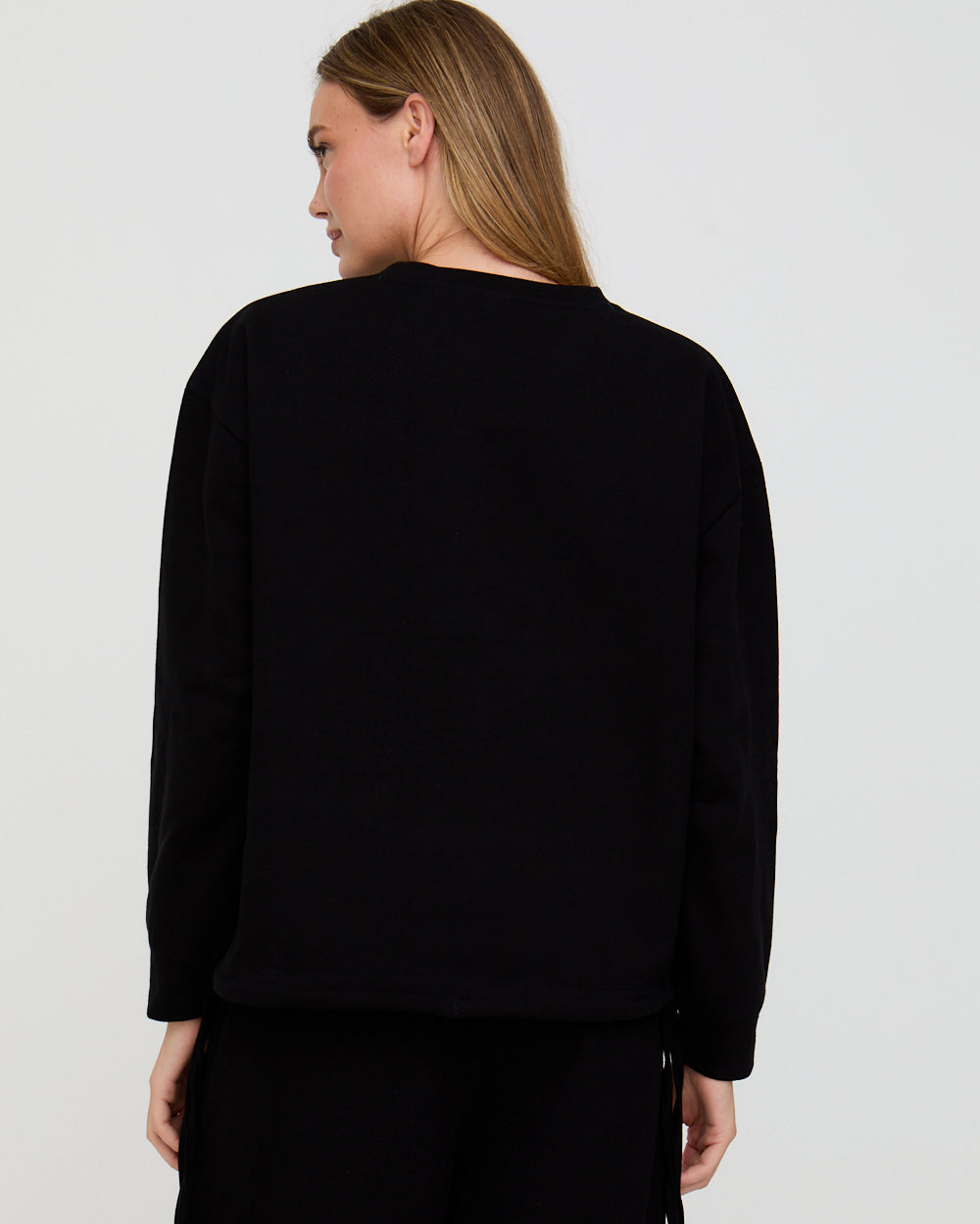 Person wearing a black sweater on a plain background