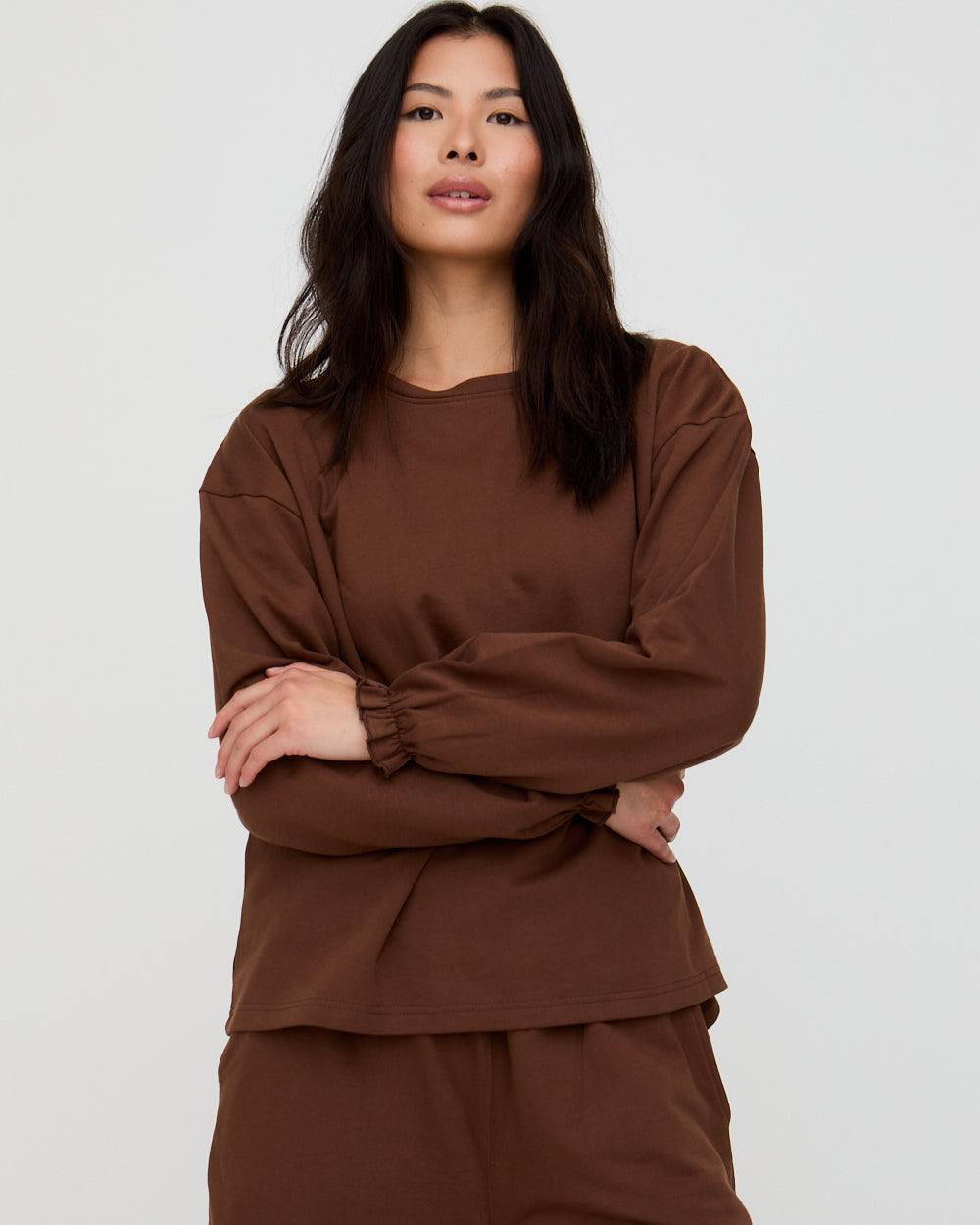Woman wearing a brown outfit against a plain background