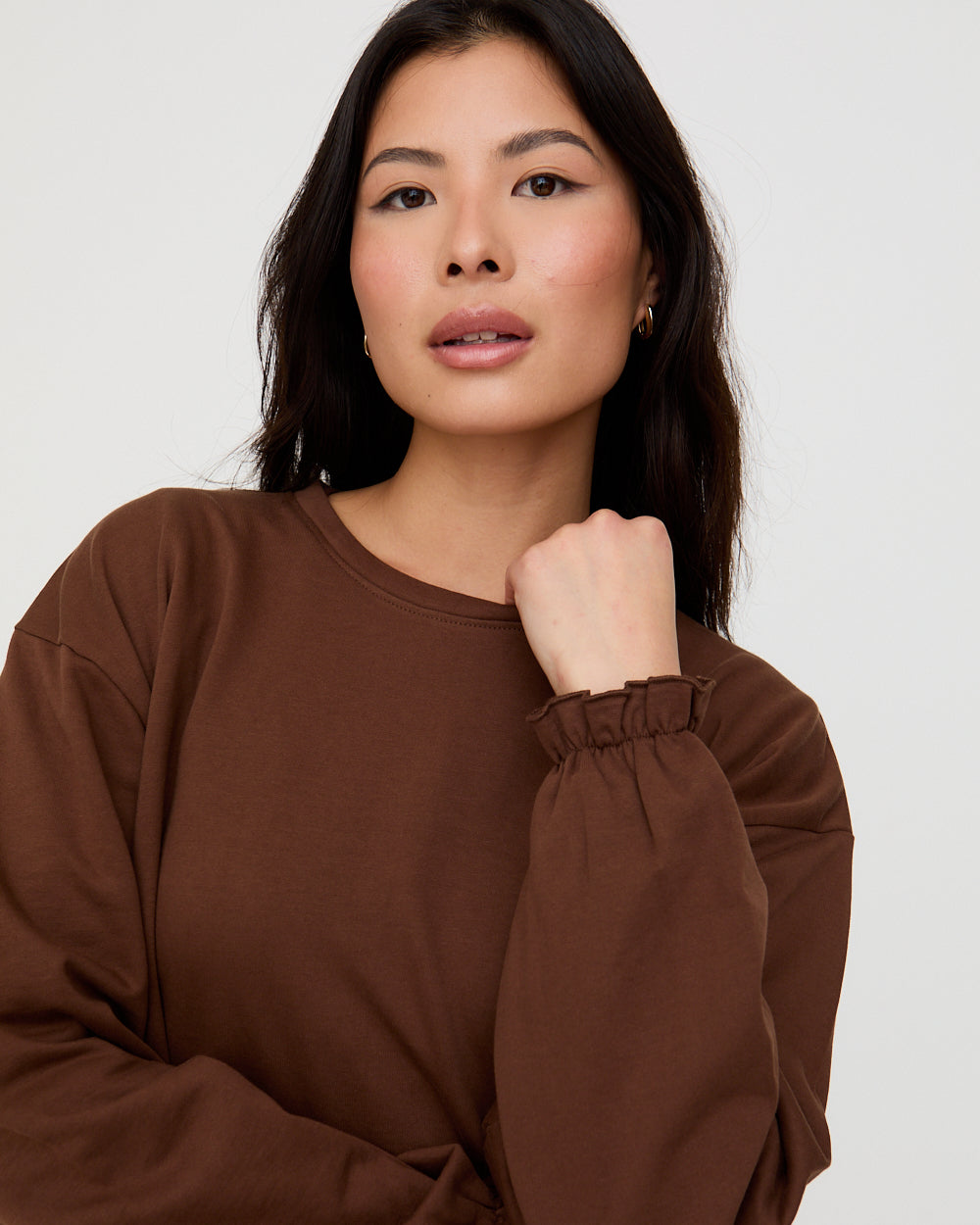 Woman wearing a brown sweatshirt against a white background