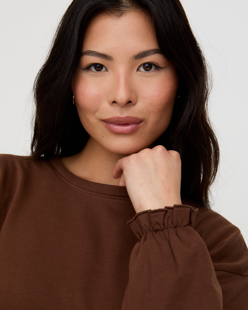 Woman wearing a brown sweater against a white background