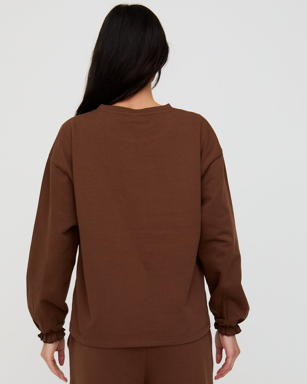 Person wearing a brown sweatshirt on a white background