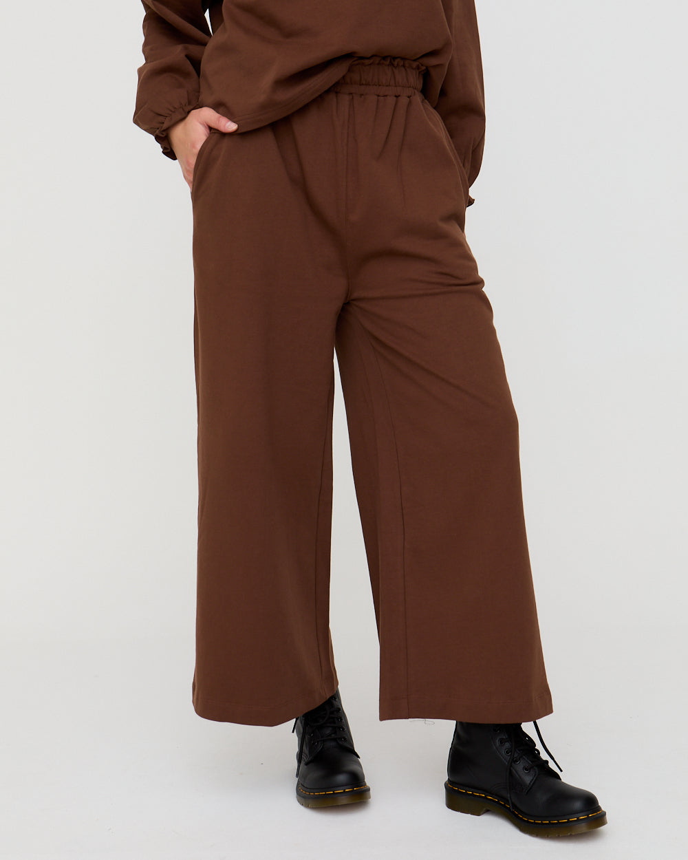 Brown wide-leg pants worn with black shoes on a white background