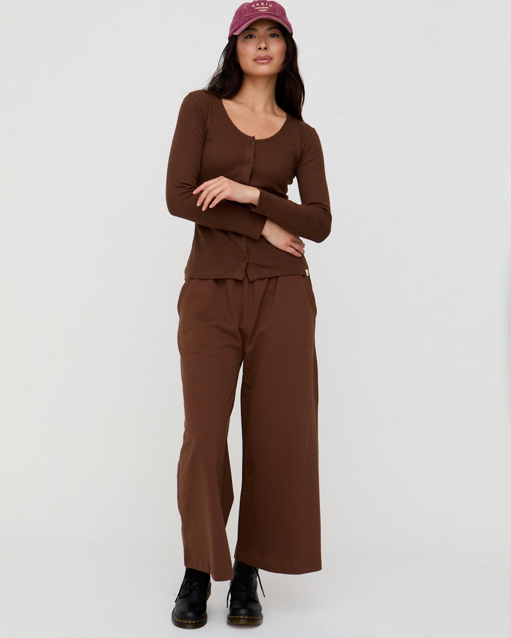 Woman wearing a brown outfit with wide-leg pants and a matching top on a white background