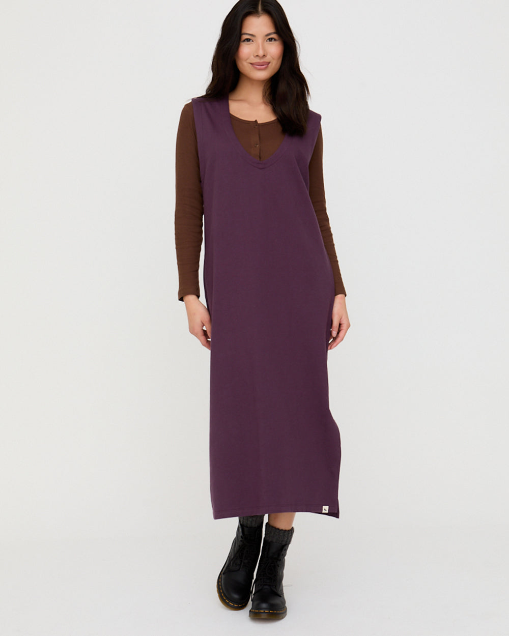 Woman wearing a long purple dress with brown sleeves on a white background