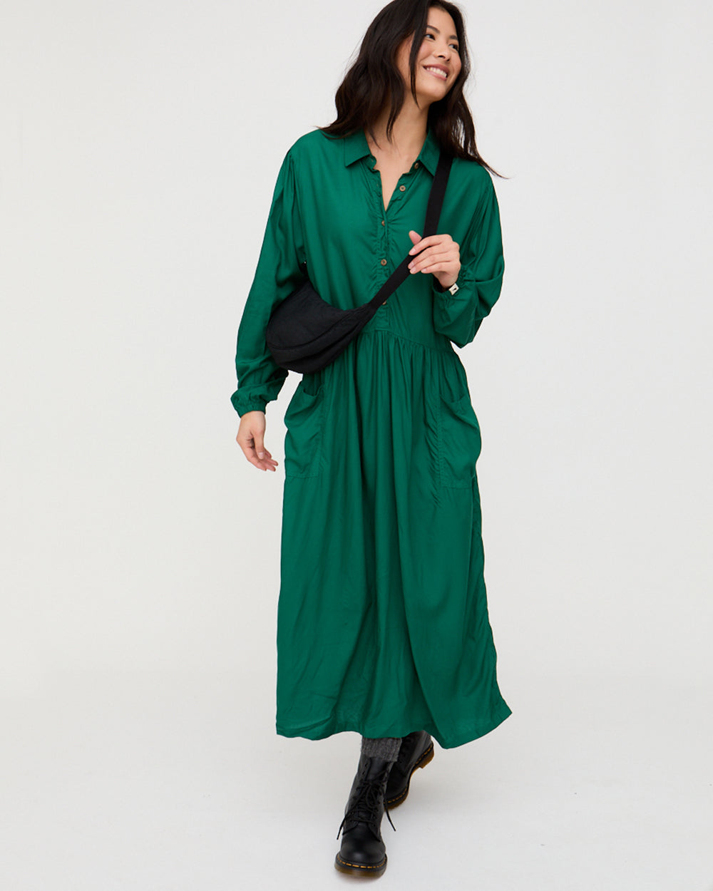 Woman wearing a green dress with a black bag on a white background