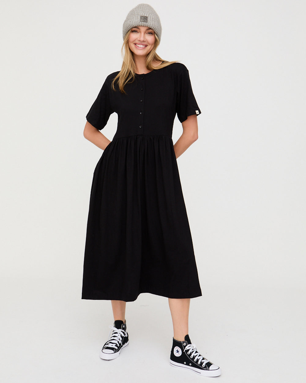Woman wearing a black dress and gray beanie on a white background