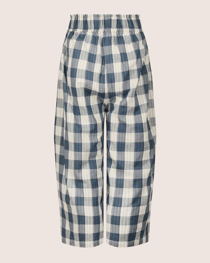 Back view of Judy Reversible Blue Check Trousers—loose-fitting, high-waisted, and cropped—with an elasticated waistband, crafted from organic cotton in a blue and white gingham check pattern against a plain white background.