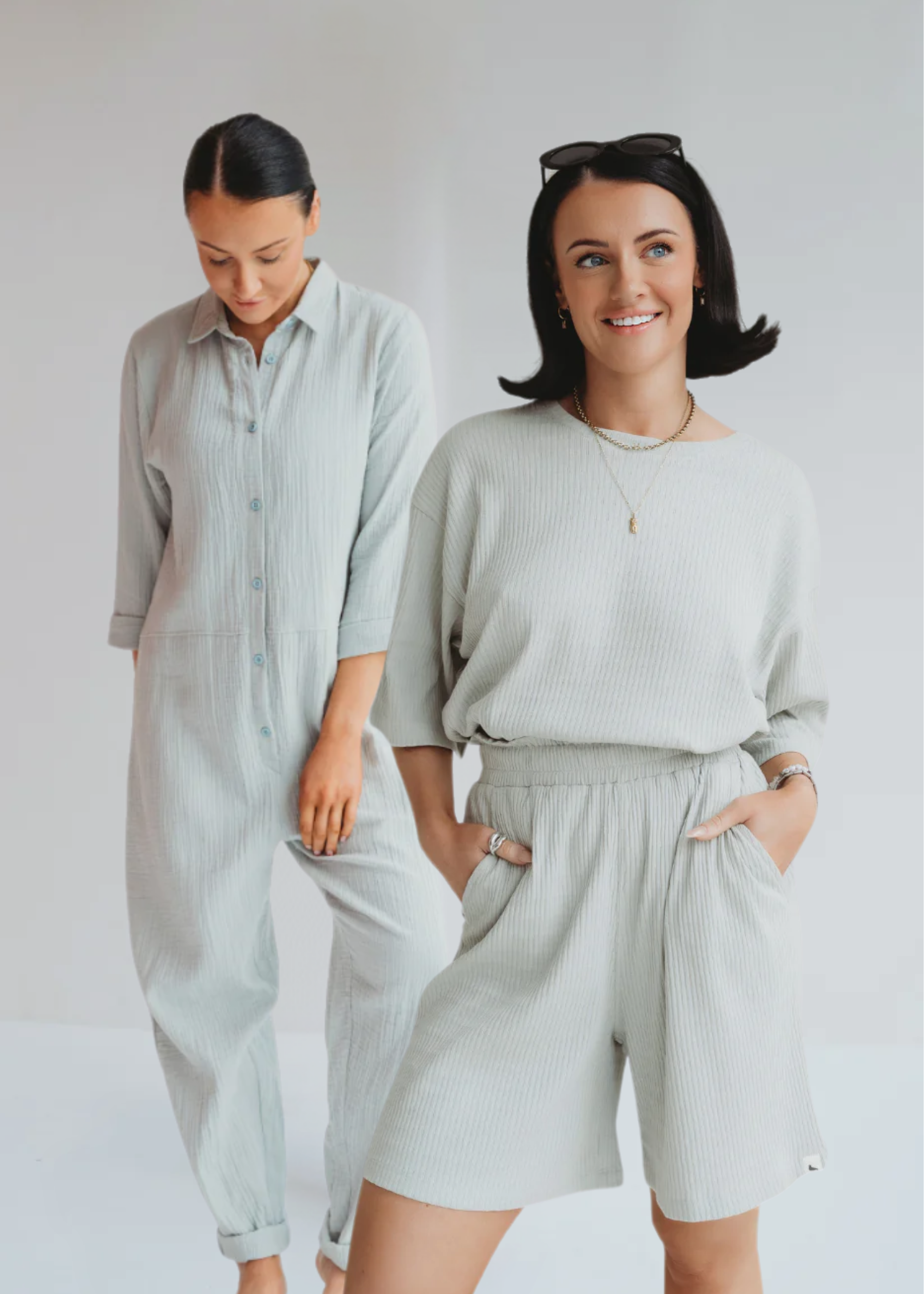 2 models standing wearing TurtleDove items. First girl wears ribbed organic cotton trousers and top in sky blue and the other a lightweight ribbed jumpsuit. 