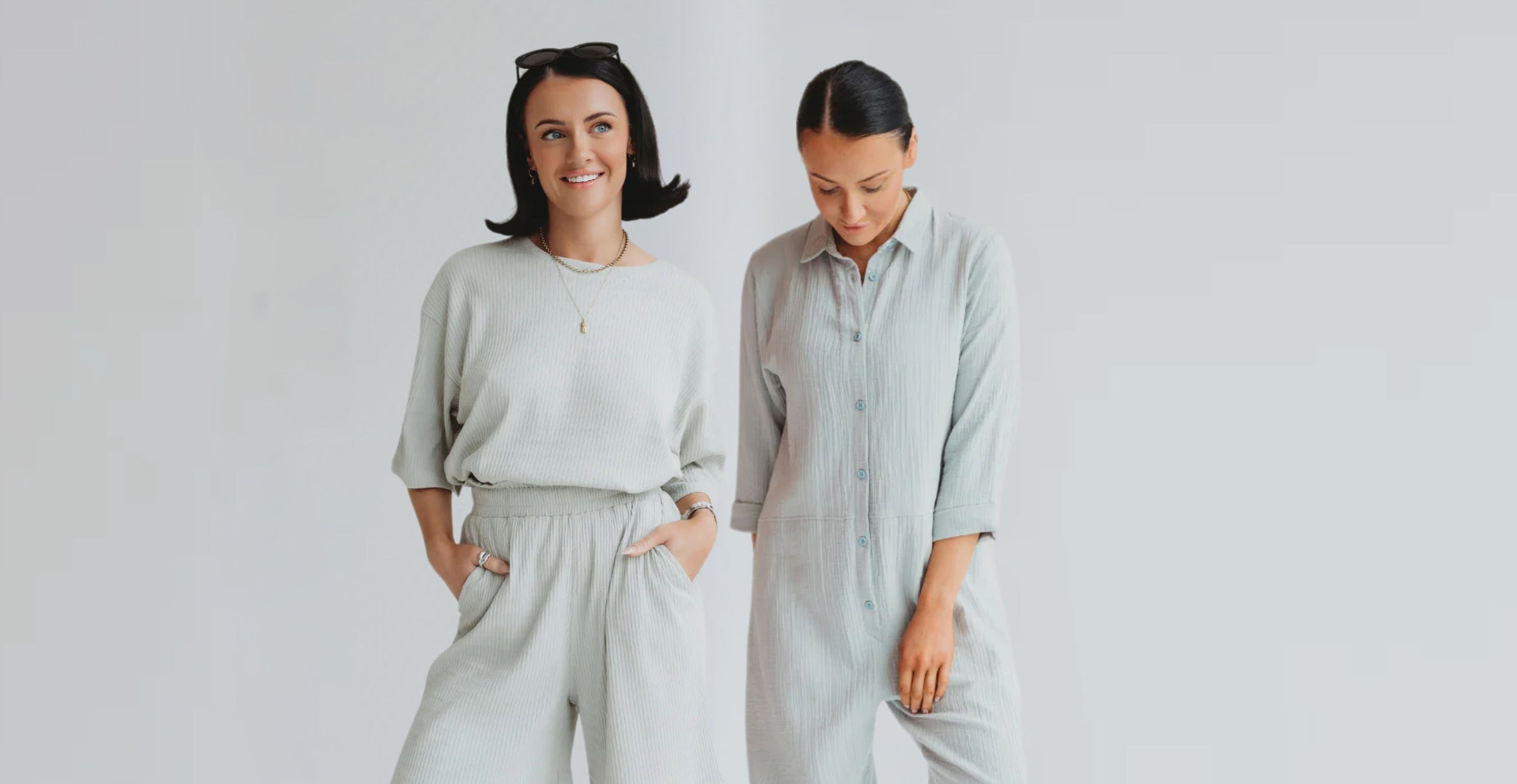 2 models standing wearing TurtleDove items. First girl wears ribbed organic cotton trousers and top in sky blue and the other a lightweight ribbed jumpsuit. 