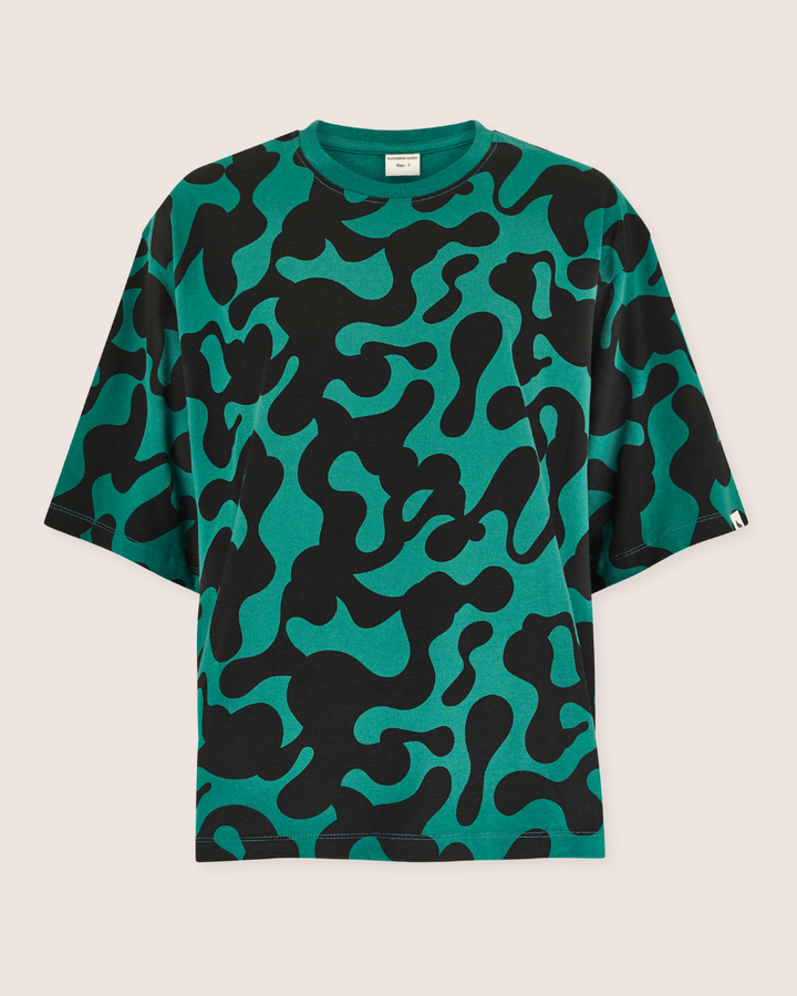 The Elsie Misty Print T-Shirt showcases a bold, abstract pattern with black and green shapes. Its made from organic cotton, featuring a crew neckline and short sleeves for ultimate comfort and style.