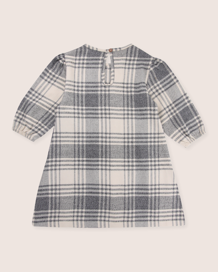 Meet the Brushed Check Dress, ideal for capsule wardrobes. Made from organic cotton, it showcases a classic gray and white plaid design with a round neckline and long sleeves. A back buttoned keyhole cutout adds a touch of elegance.