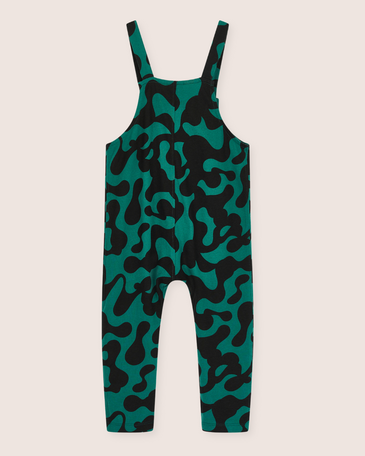 Misty Print Dungarees are crafted from organic cotton jersey with a light beige background, showcasing green overalls with black abstract patterns. These gender-neutral kids dungarees feature adjustable shoulder straps and a straight-cut design for a stylish and sustainable wardrobe choice.