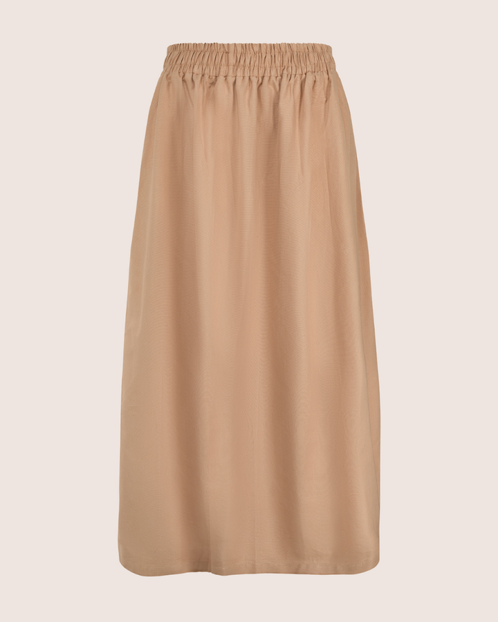 The Joyce Easy Fit Clay Skirt is a versatile beige midi piece with an elastic waistband and straight silhouette, ideal for a sustainable wardrobe.