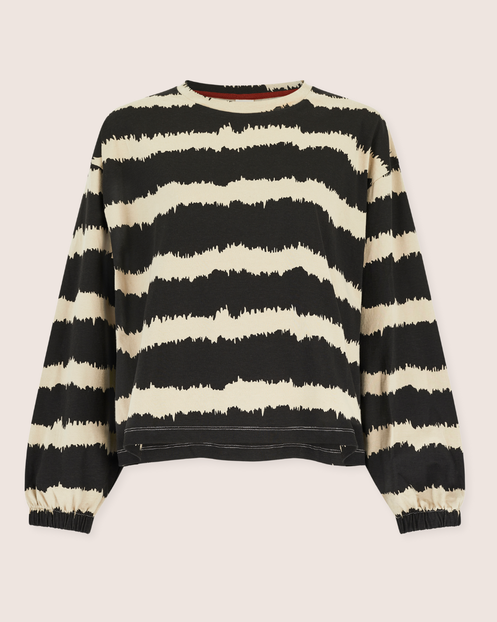 The Ivy Drift Print Top is a sustainable, stylish long-sleeved sweater in organic cotton with black and cream brushstroke-like stripes. Featuring a relaxed fit, rounded neckline, and elastic cuffs, it offers a chic yet casual silhouette against a neutral background.