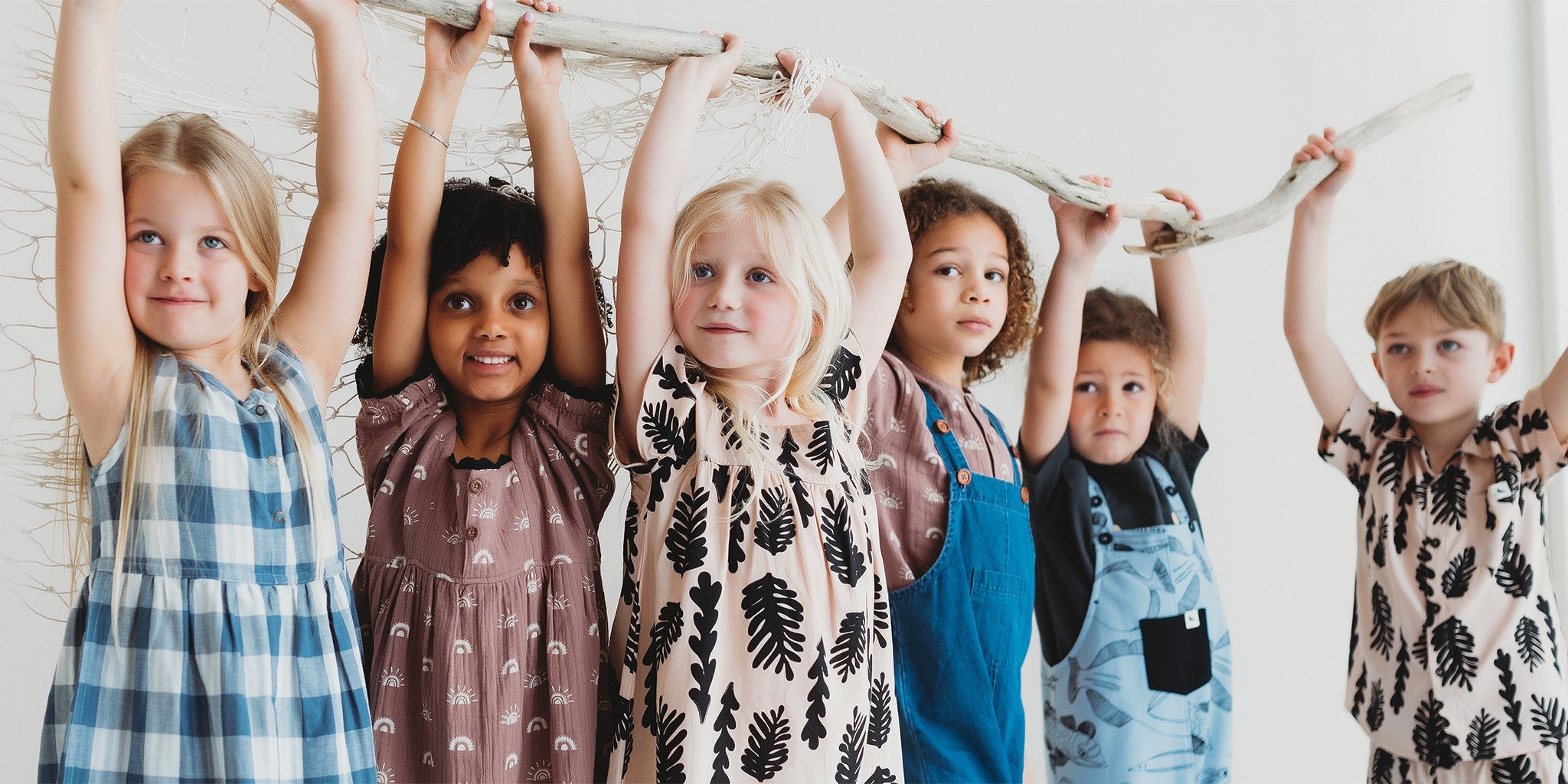 kids hanging from a branch wearing turtledove organic kids clothes 