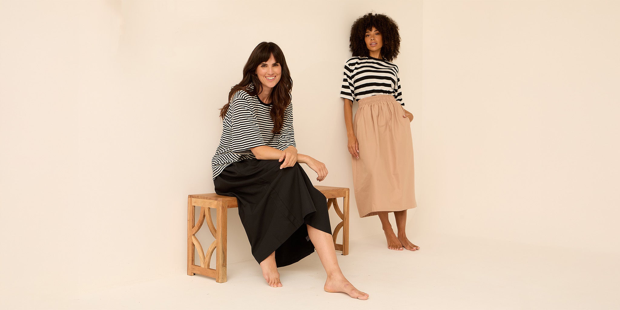 Two women wearing striped tops and skirts on a beige background