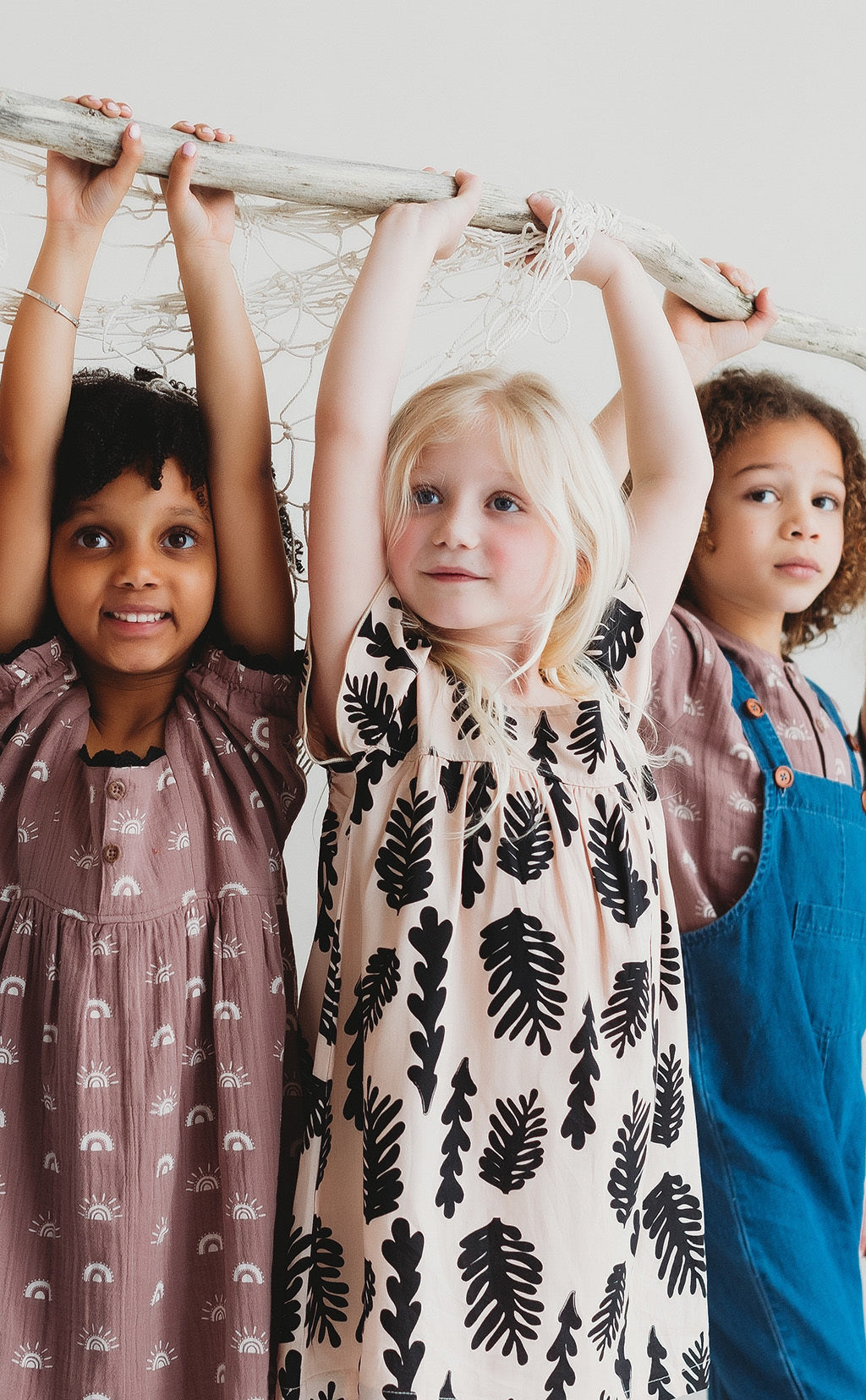 kids hanging from a branch wearing turtledove organic kids clothes 