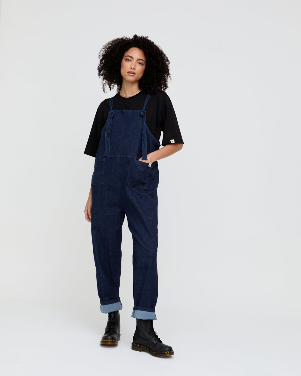 Person wearing navy blue overalls on a white background