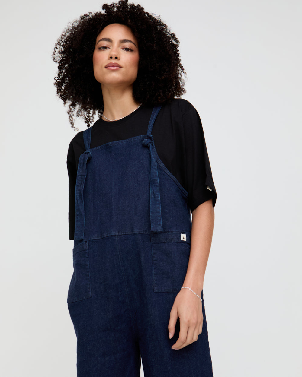 Woman wearing navy blue overalls on a plain background