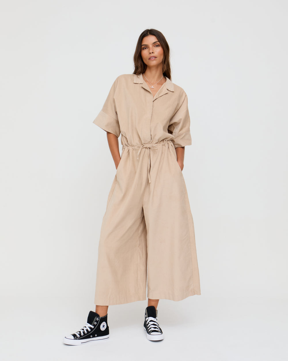 Woman wearing a beige jumpsuit with a white background