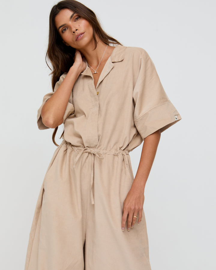 Woman wearing a beige jumpsuit on a white background
