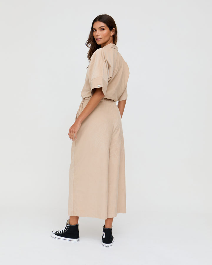 Woman wearing a beige dress with a plain background