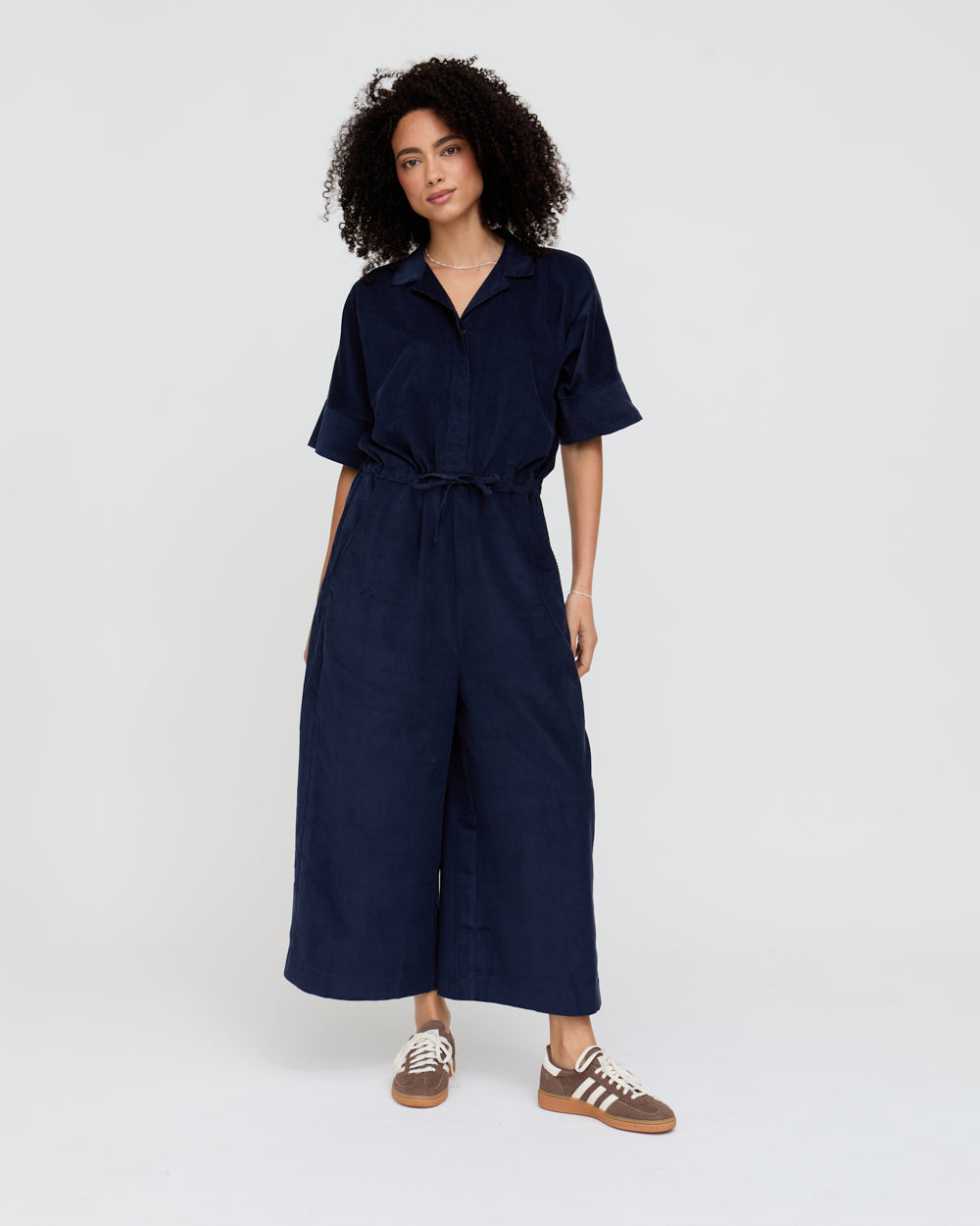 Woman wearing a navy blue jumpsuit on a white background