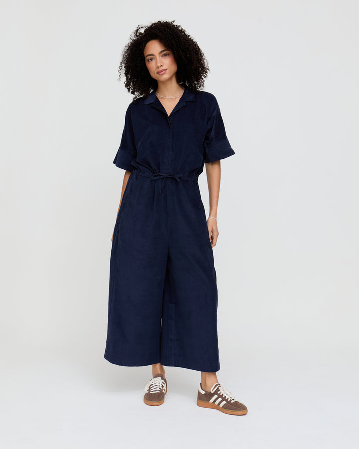 Woman wearing a navy blue jumpsuit on a white background