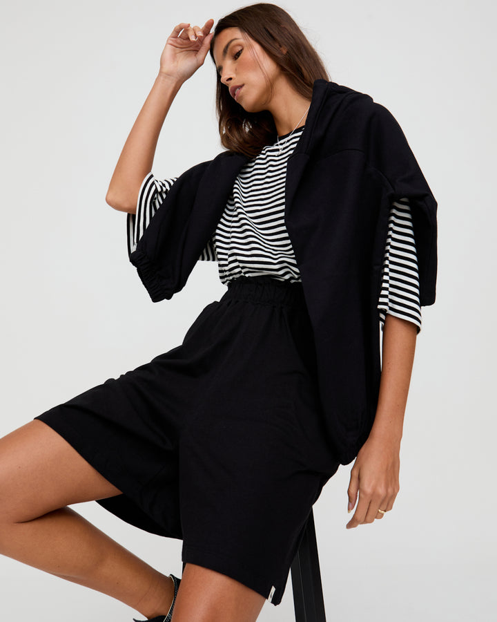 Woman wearing a black outfit with a striped shirt on a white background
