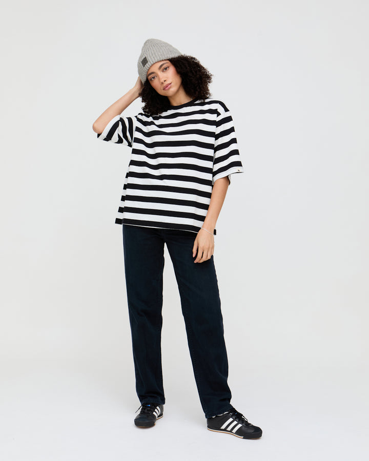 Person wearing a black and white striped shirt, dark pants, and a gray beanie on a white background