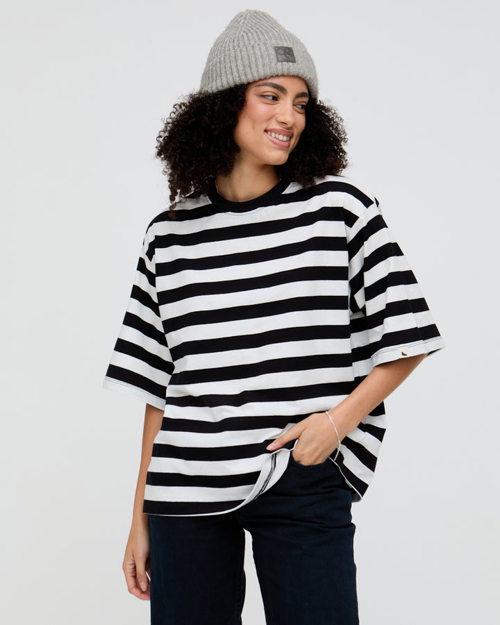 Person wearing a black and white striped shirt and gray beanie on a light gray background