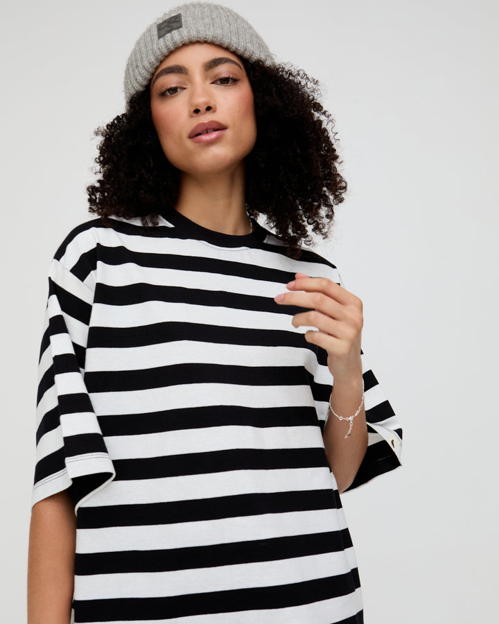 Person wearing a black and white striped shirt with a gray beanie on a plain background