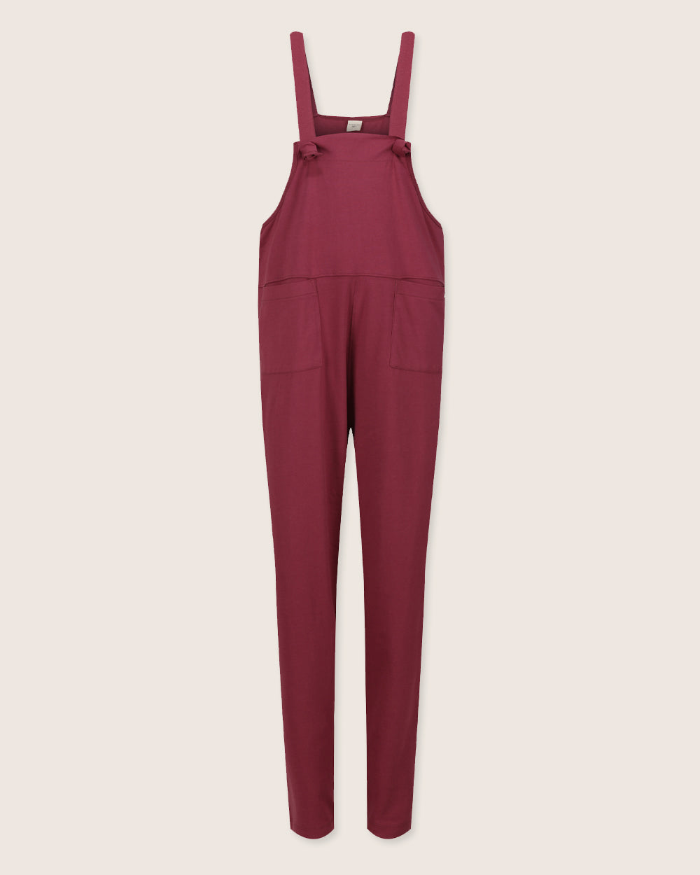 The Lila Burgundy Dungarees, made from organic cotton with adjustable shoulder straps and two front pockets, are displayed on a light background. Perfect for sustainable fashion enthusiasts.